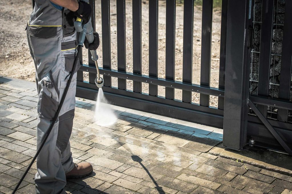 A professional power washer cleaning a driveway in Roswell, GA