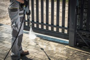 A professional power washer cleaning a driveway in Roswell, GA